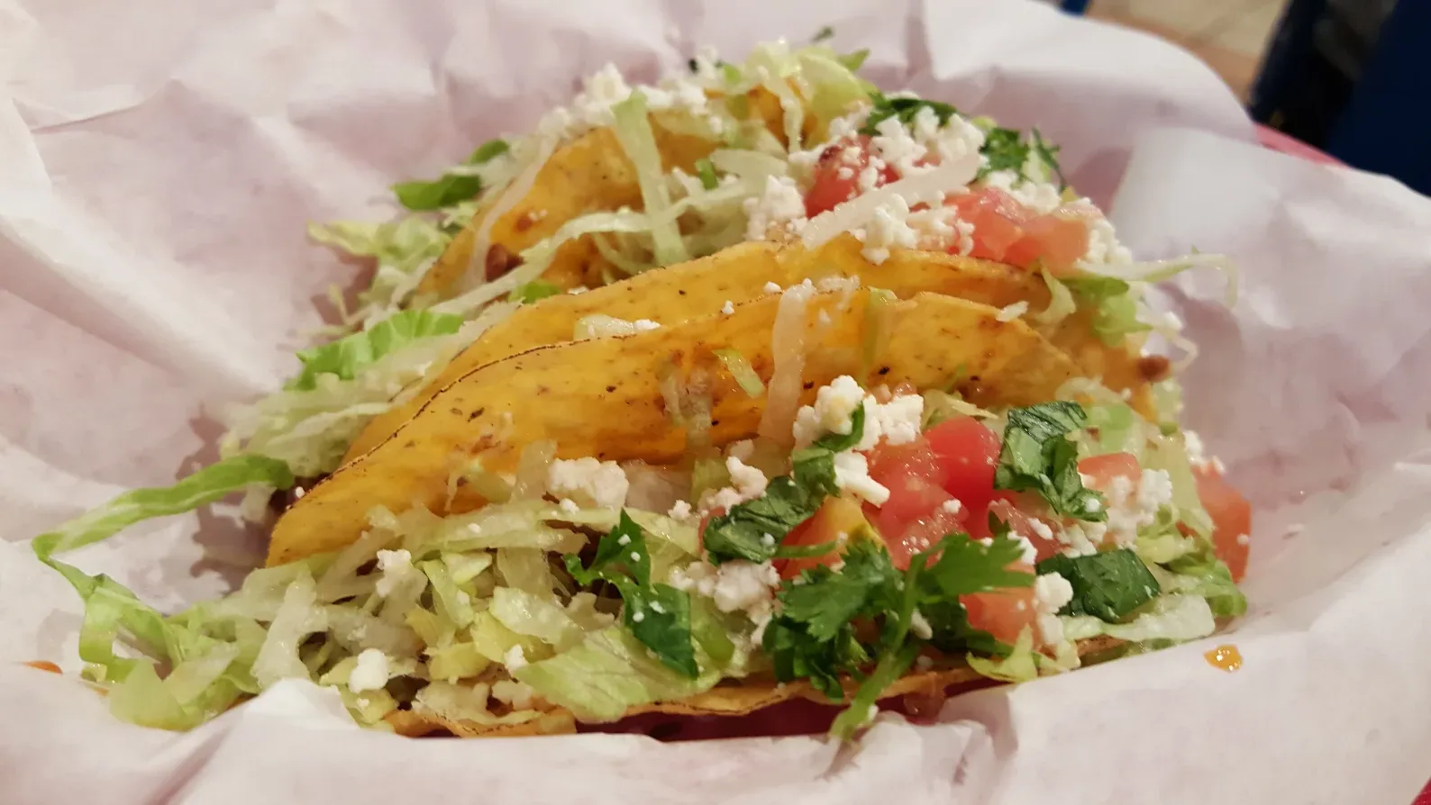 Mexican taco with salad and cheese on paper wrap